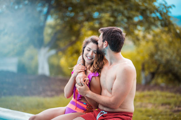 istock Happy smiling couple sitting on the pool. 1310239867