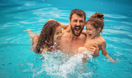 Father with kids playing in the pool.