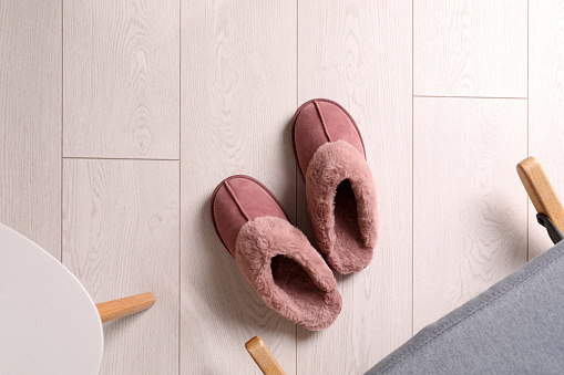 Pink warm slippers on floor indoors, flat lay