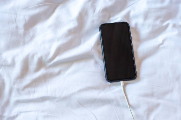 istock mobile smart phone charging battery on bed in the bedroom at home. Technology, multiple sharing and lifestyle concepts 1310243546