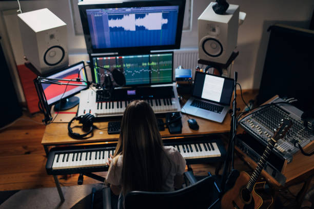 istock Female modern music producer, working from her well equipped music studio, while digital recording chords she play on the electric keyboard 1310243907