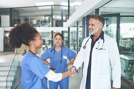 Cropped shot of an attractive young nurse standing and shaking a doctor's hand in the clinic