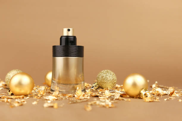 unbranded black and gold perfume spray bottle, gold christmas balls and paper firecracker pieces on golden background. mockup with copy space. bottle for branding and label, front view, new year party - merchandise luxury still life spa treatment imagens e fotografias de stock