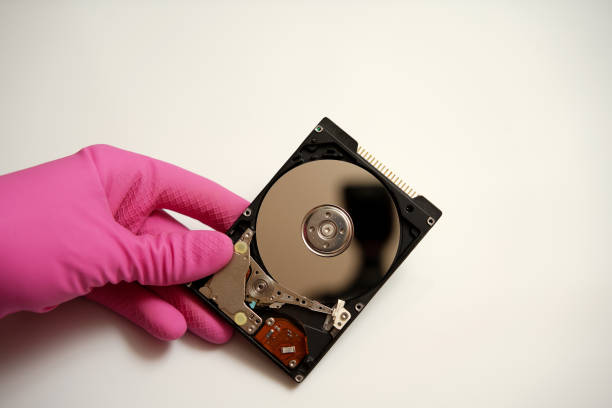 istock Disassembled hard disk of computer memory in hand in a rubber pink glove on a white background 1310249067