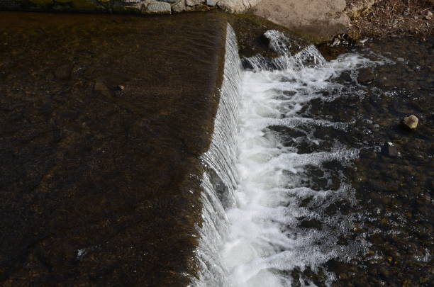 vista de um açude com falta de água para esportes aquáticos. a seca hidrológica acabou com a navegabilidade e rafting ou açude é uma barreira para remadores de peixes e jangadas - miniature weir - fotografias e filmes do acervo