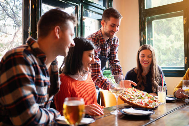 istock Friendly waiter bringing food at the table in a restaurant 1310256143