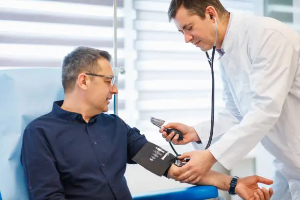 Doctor checking blood pressure to a mature male patient