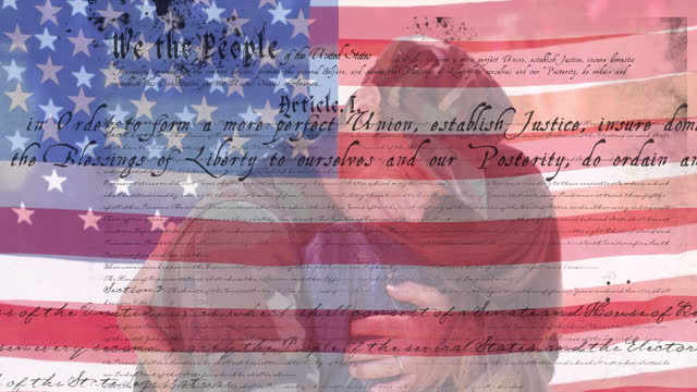 Digital composite video of us constitution text against waving us flag and american soldier hugging