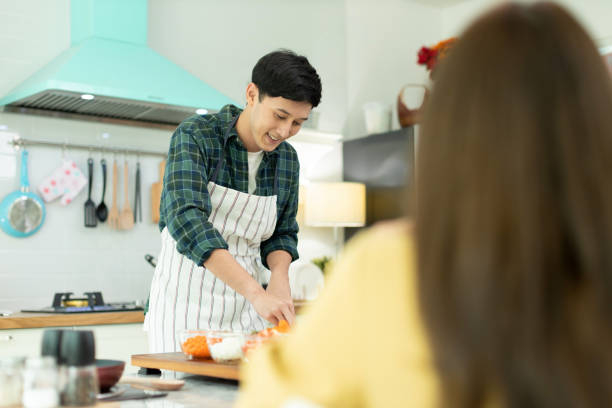 istock Husband slicing vegetables to prepare breakfast. With a young wife supporting him In a romantic atmosphere 1310262732