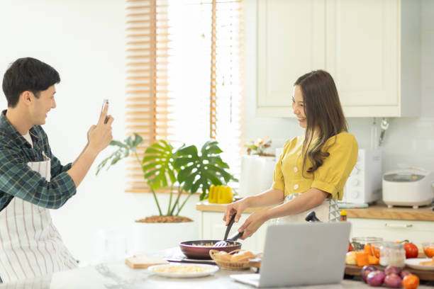 um casal usa seu telefone inteligente para tirar uma foto enquanto admira o trabalho de culinária de sua esposa com um rosto feliz em uma atmosfera de amor - smart casual occupation casual healthy eating - fotografias e filmes do acervo