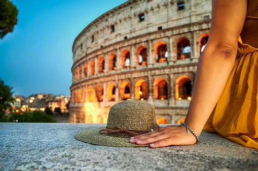 Shot of an unrecognizable woman sitting in front of the Colosseum at dusk in Rome, Italy