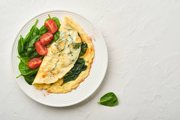 istock Omelet or omelette with spinach, cherry tomato and pepper seasoning on a white plate, on white background. Top view. 1310267171