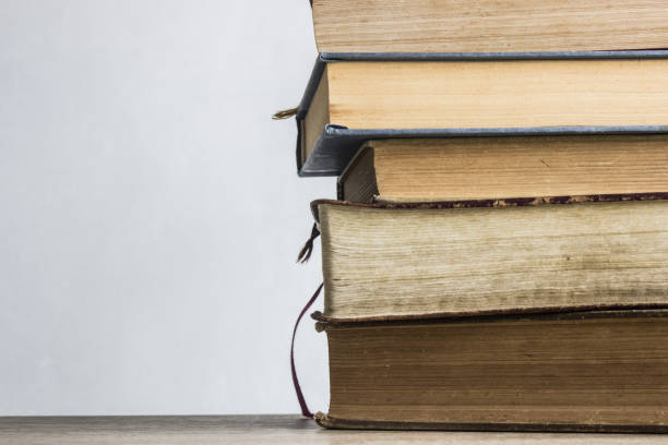 istock Stack of books on wooden table with window light 1310267307