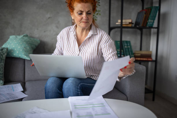 istock Mature redhead woman checking her finances while sitting on sofa at home 1310267474