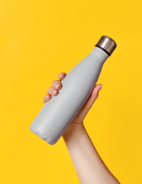 istock Hand with grey reusable insulated bottle on yellow background 1310268902