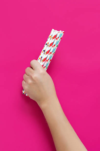 istock Hand with paper drinking straws on pink background close up 1310268908
