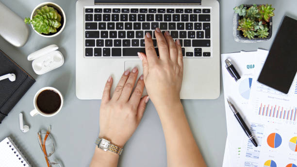 istock Woman hands typing with laptop on a grey office desk top view 1310268911