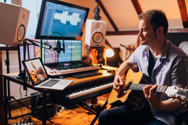 istock Musician, from his modern home studio, leading a guitar class, via video call, teaching his young female student te new guitar chords 1310269576
