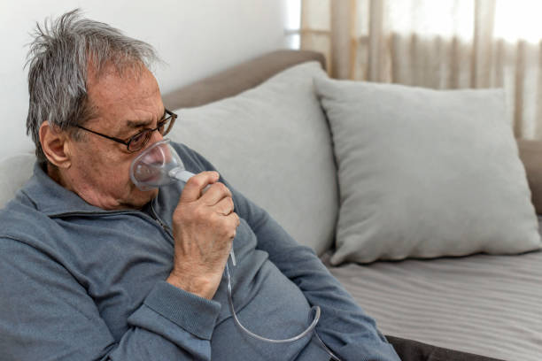 o homem caucasiano idoso faz inalação com uma máscara de nebulização em casa para doença coronavírus - medical oxygen equipment healthcare and medicine 70s mature adult - fotografias e filmes do acervo