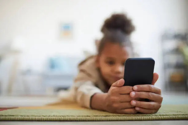 Photo of African American Girl Using Smartphone on Floor