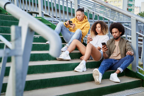 istock Three young people sitting on stairs with mobile phones 1310274920