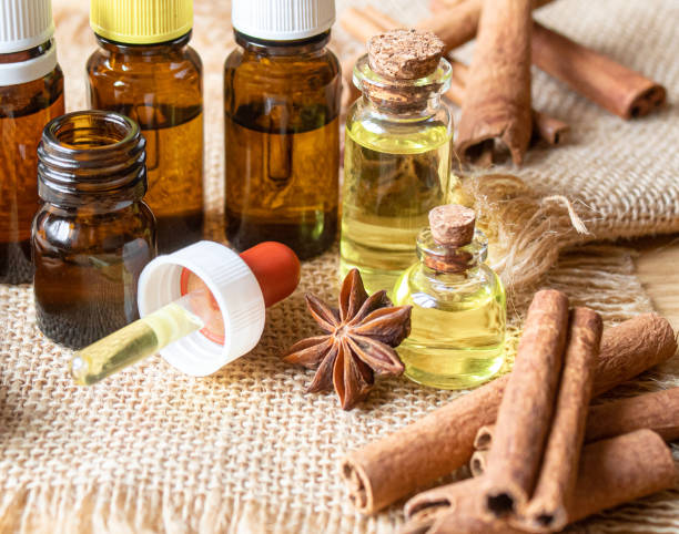 istock Essential oil bottle with cinnamon stick, star anise on wooden background. Selective focus 1310278095