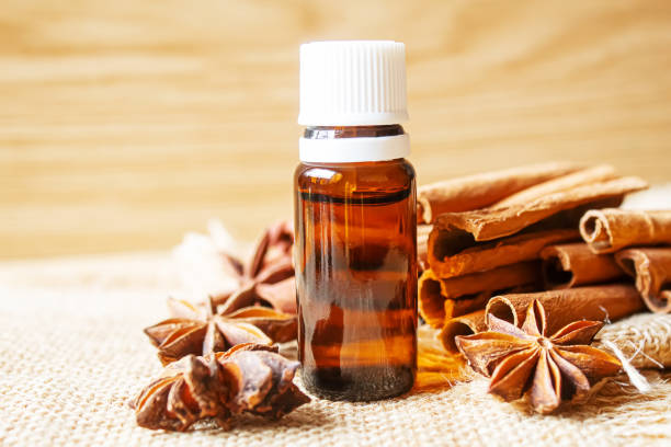 istock Essential oil bottle with cinnamon stick, star anise on wooden background. Selective focus 1310278097