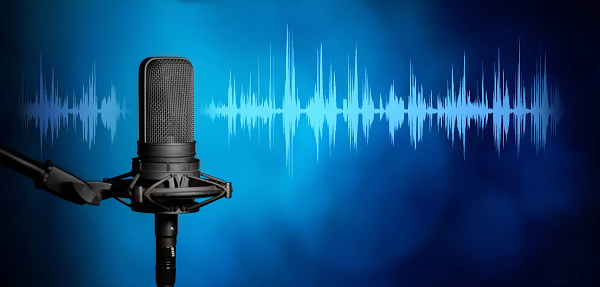 Close up of Young smiling man recording podcast and doing live streaming using microphone and headphones in recording studio