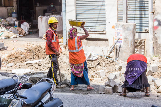 mujeres trabajan en una obra de construcción cerca de la carretera en una ciudad bajo proyecto de ciudad inteligente por el gobierno indio - editorial indian culture traditional culture horizontal fotografías e imágenes de stock