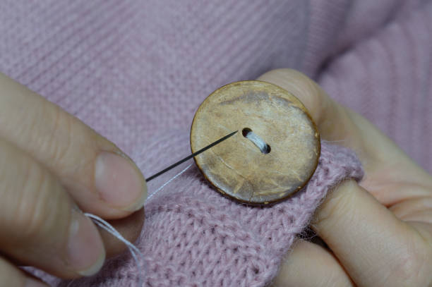 istock female workers' hands sew a wooden button to a jacket. close-up. 1310280658