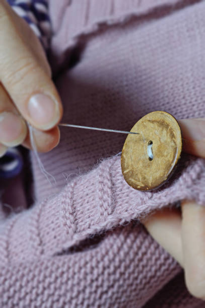 istock female workers' hands sew a wooden button to a jacket. close-up. 1310280710