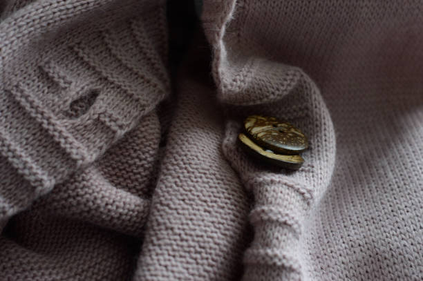 istock female workers' hands sew a wooden button to a jacket. close-up. 1310280730
