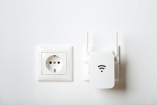 white wi-fi repeater indoors at home in outlet. wireless router.