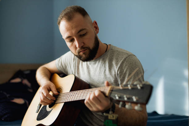 istock A young man is playing on the acoustic guitar at home 1310282376