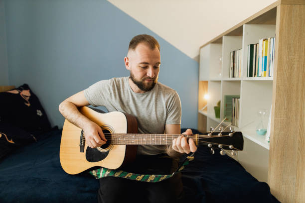 istock A millennial is playing on the acoustic guitar at home 1310282487