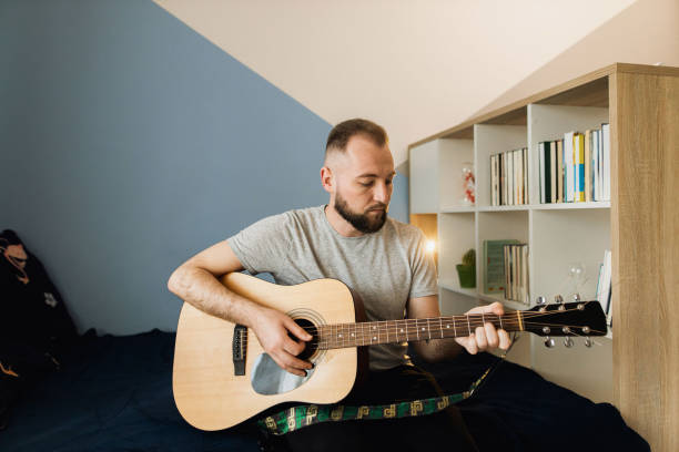 istock A millennial is playing on the acoustic guitar at home 1310282506