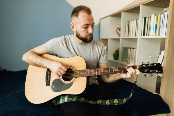 istock A millennial is playing on the acoustic guitar at home 1310282519