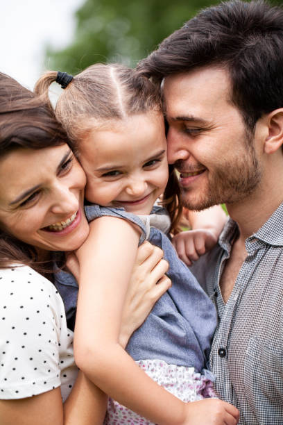 istock Smiling parents embracing daughter outdoors 1310284848