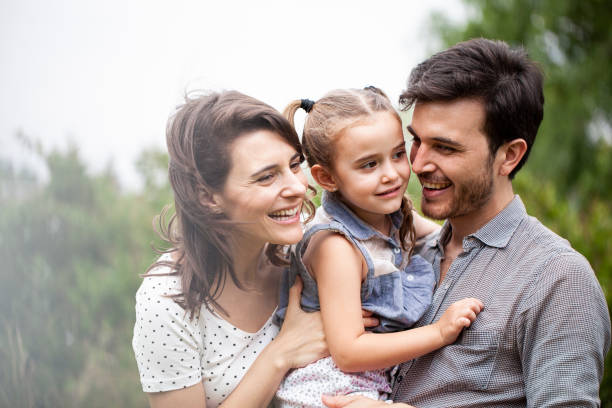 istock Smiling parents embracing daughter outdoors 1310285010
