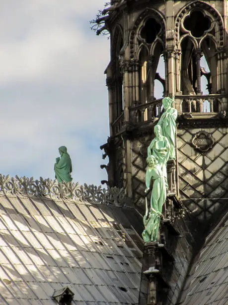 Detail and green oxidized bronze statues on the iron spirelet on the roof of the Notre-Dame Cathedral, Paris