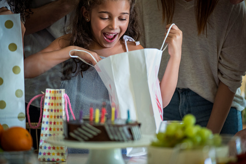 Surprised girl looking at her birthday gift on the dining table at home