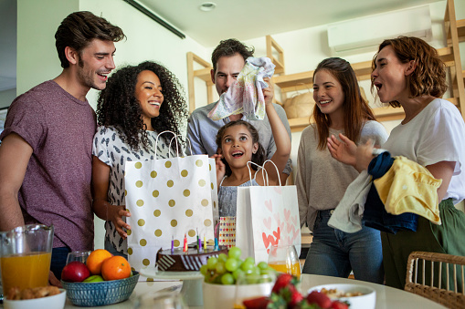 Smiling girl looking at her birthday gift while celebrating birthday with family at home