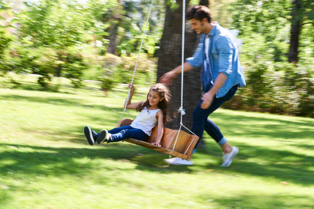 istock Father and daughter playing on the swing in garden 1310289428