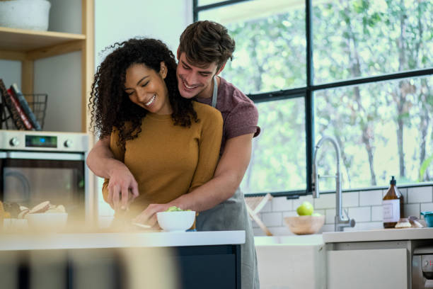 istock Smiling couple preparing food together in kitchen 1310289585