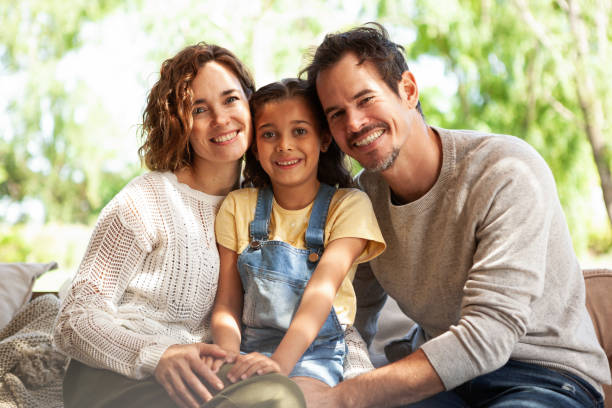 Smiling parents sitting with their daughter on sofa stock photo