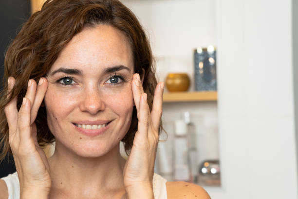 istock Close-up of woman applying cream to her face using both hands 1310290726