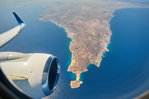 The plane is flying over the island of Cyprus. Airplane wing in flight from window.