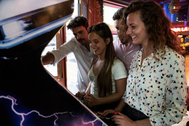 Young friends playing on arcade game machine at bar