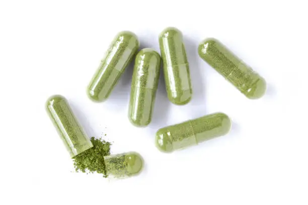 Photo of green herbal powder medicine capsules pills isolated on white