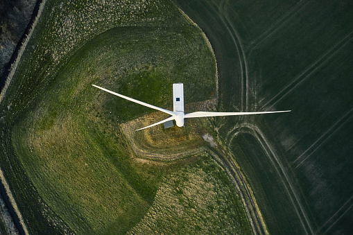 3D Rendering of Giant wind turbines farm located in the open sea, sunset shot. Concept of renewal energy using windmills.